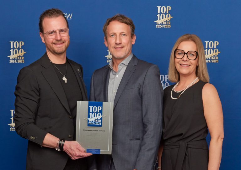 Wotan Wilke Möhring überreicht die TOP 100 Optiker-Auszeichnung an Heinemann-Geschäftsführer Ralf Sandner (li.) und seine Frau Anja.